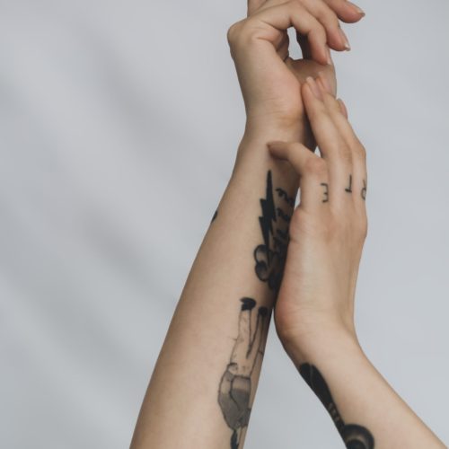 close-up-woman-holding-hands-with-tattoo-white-background