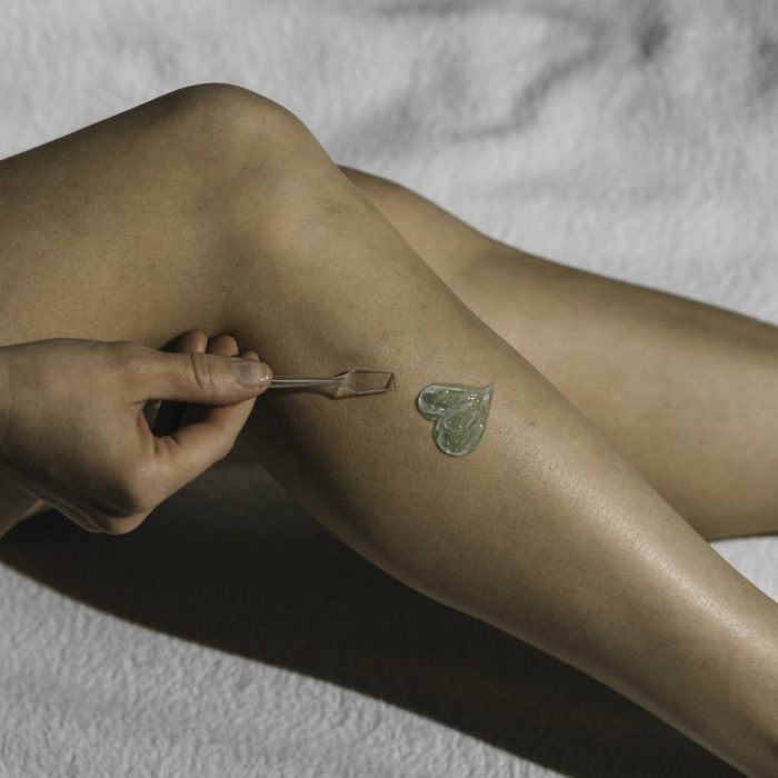 Woman Body Care. Close Up Of legs. Epilation concept. Spa, skin care and wellness. Aloe vera gel in the shape of a heart. White background, copyspace.